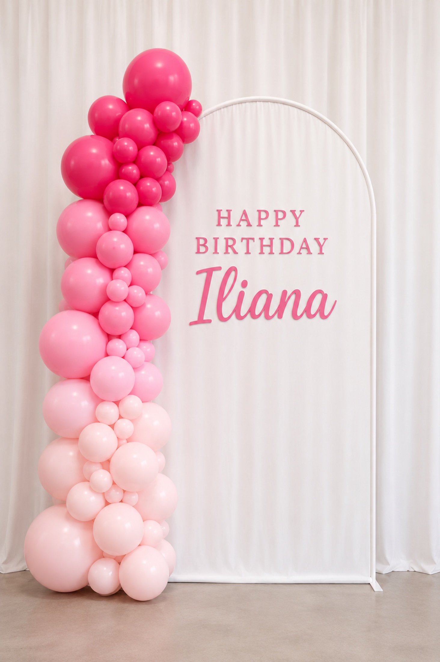 Pink ombre balloon garland beside a personalized birthday arch